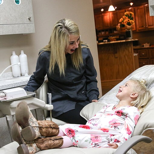 One of our Dental Assistants laughing next to a little girl 